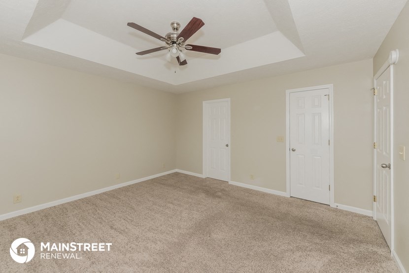 the living room of a home with carpet and a ceiling fan