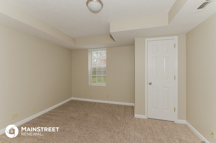 a bedroom with a white door and a carpeted floor