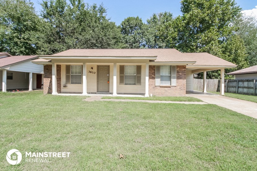 a small brick house with a grassy yard and trees