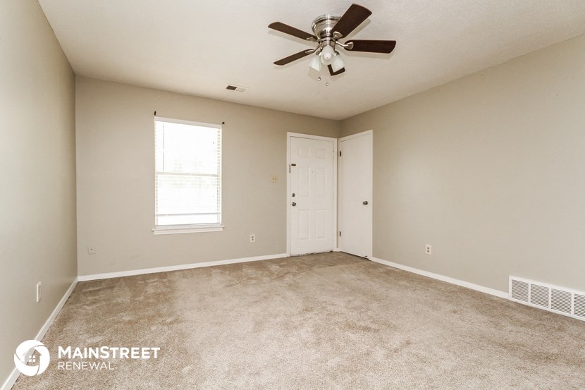 an empty living room with a ceiling fan and a window