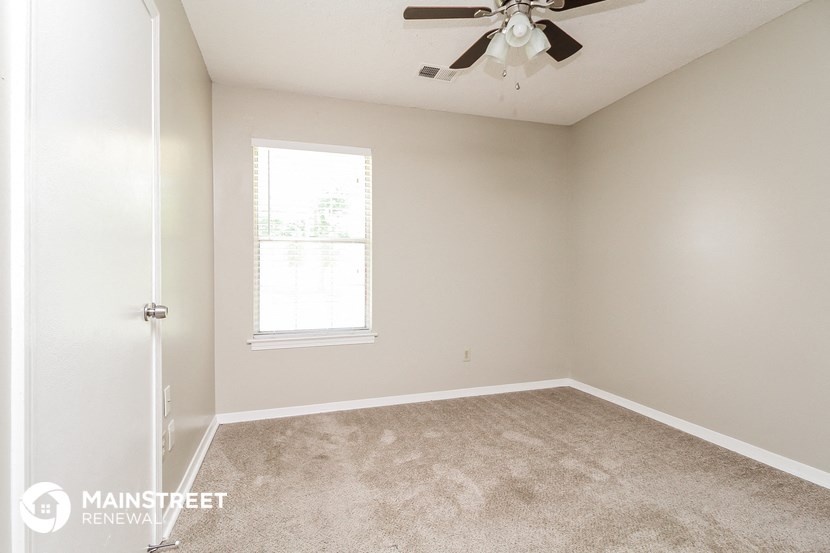 an empty bedroom with a ceiling fan and a window