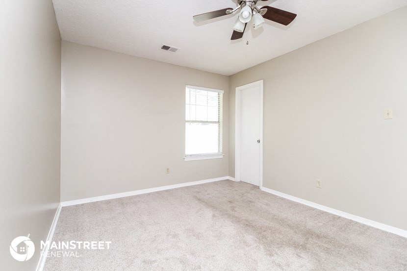 an empty living room with a ceiling fan and a window