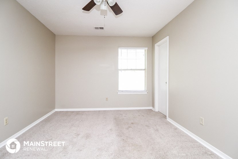 an empty room with a ceiling fan and a window