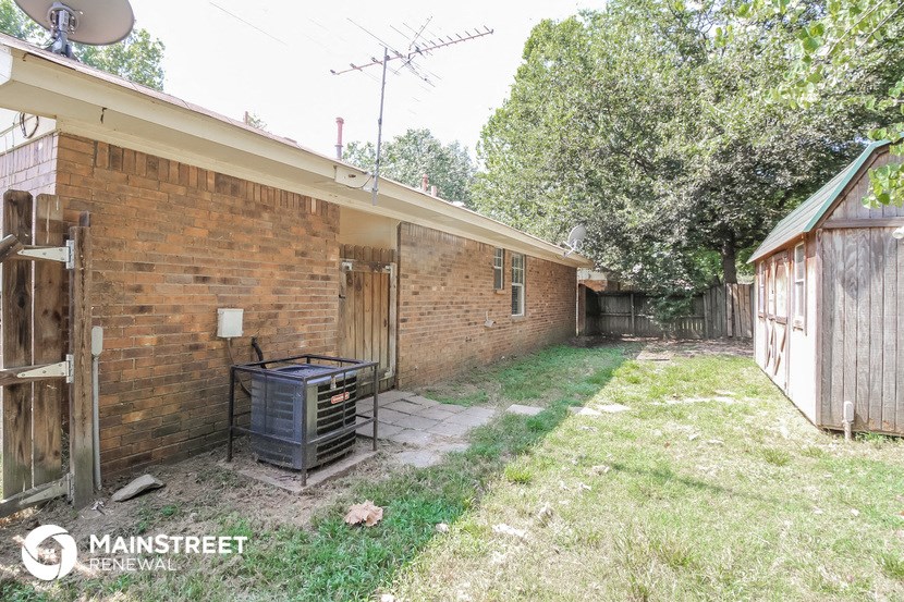 the backyard of a brick house with a grill in the yard