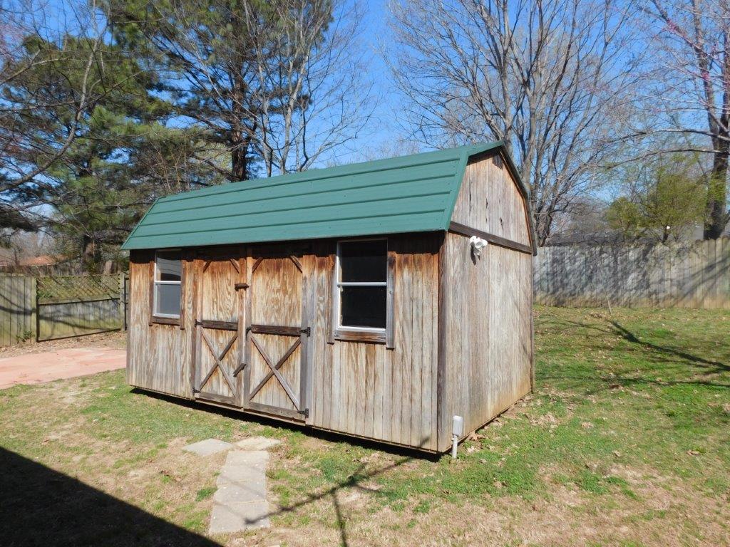 a wooden shed with a green roof and barn doors