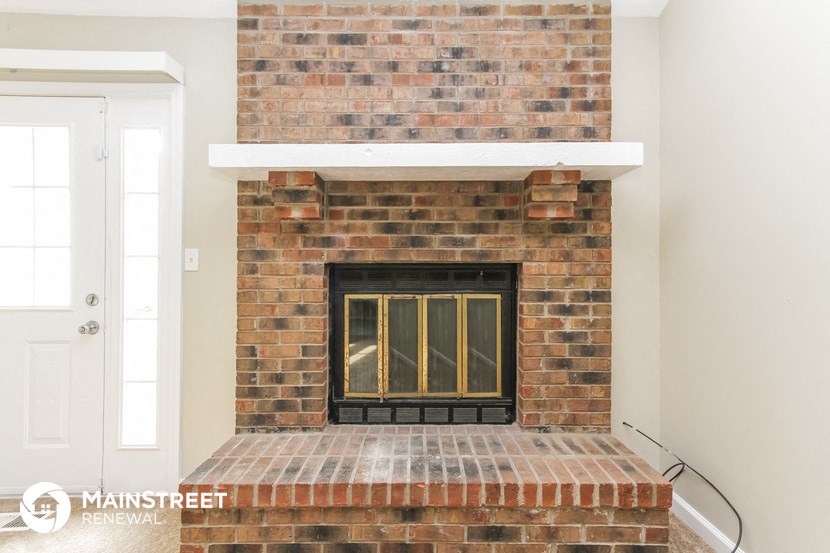 the living room has a brick fireplace with a mantle and a window