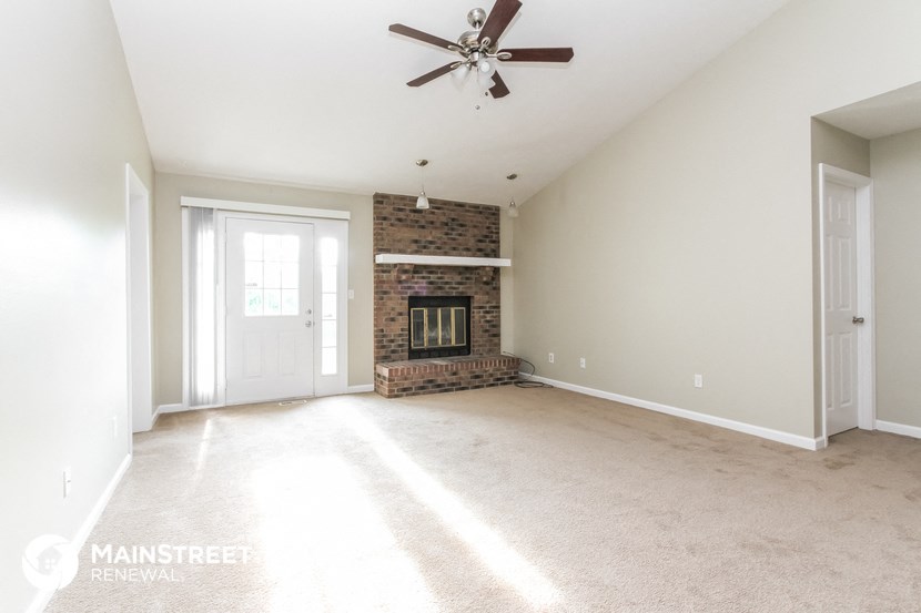 an empty living room with a fireplace and a ceiling fan