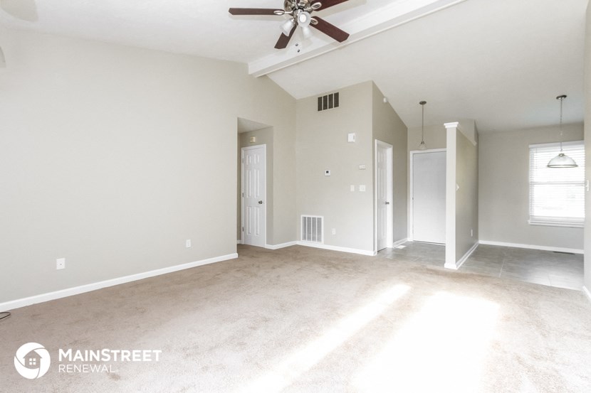 an empty living room with a ceiling fan