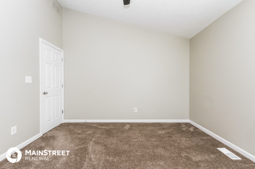 the spacious living room with carpeting and a door to the bedroom