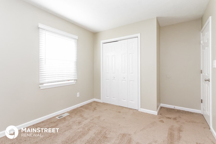 a bedroom with a carpeted floor and a white door and window