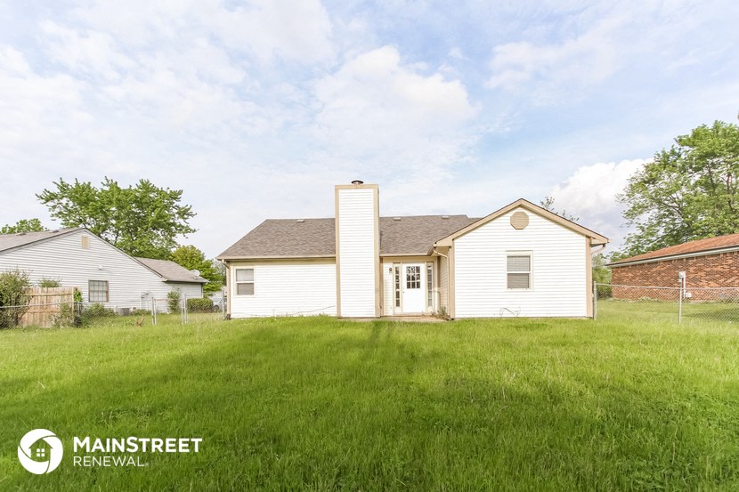 a view of the back of a white house in a grassy yard