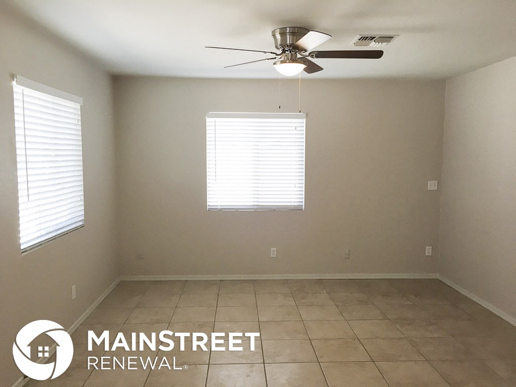 an empty room with a ceiling fan and two windows