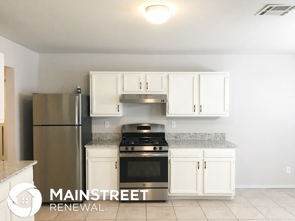 an updated kitchen with white cabinets and stainless steel appliances