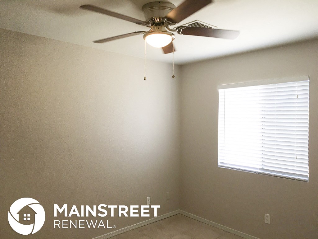 an empty room with a ceiling fan and a window
