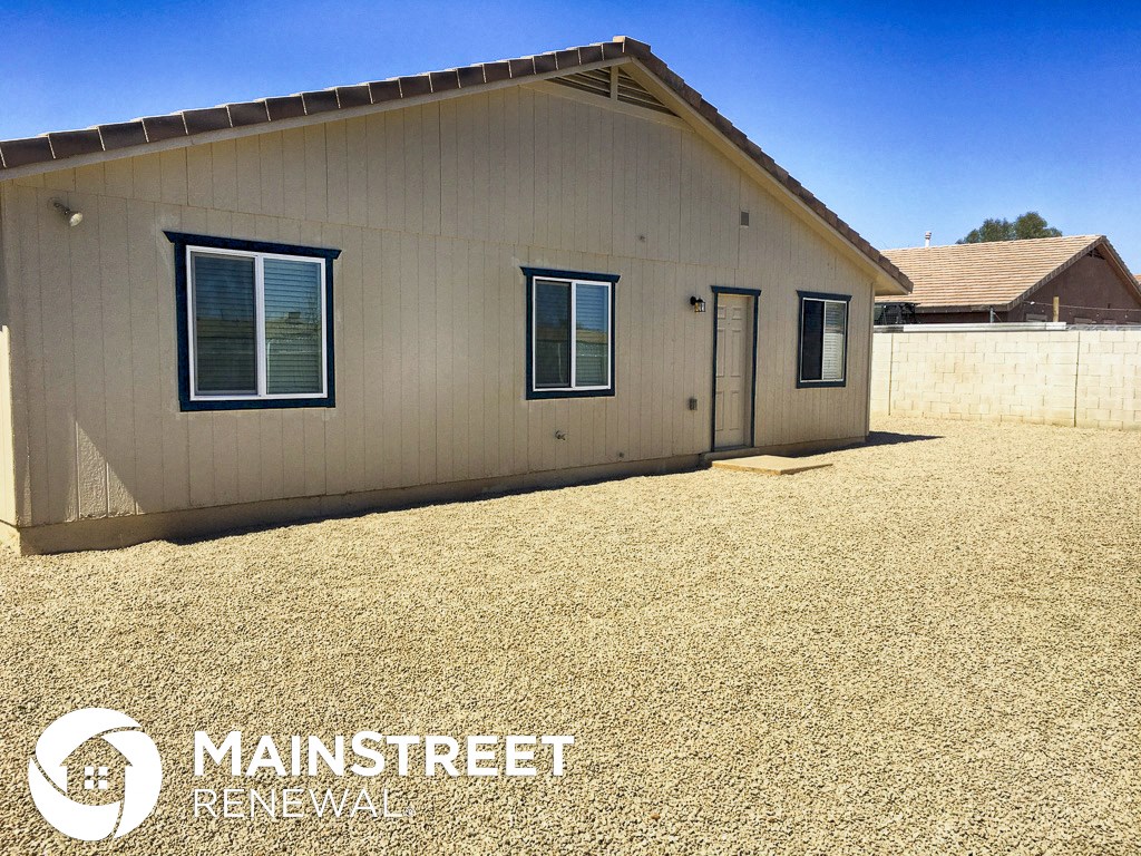 a small house with a gravel yard and a garage