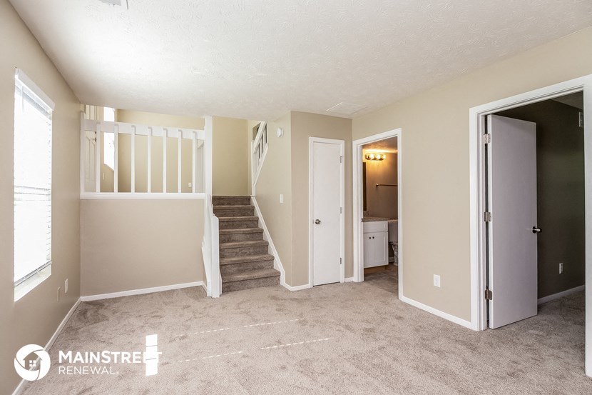 a living room with a staircase and a door to a bathroom