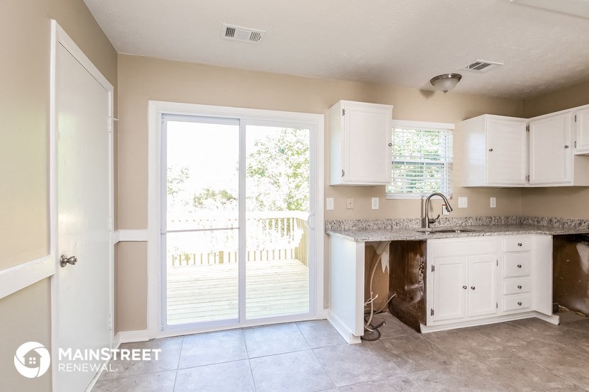 a kitchen with white cabinets and a door to a patio