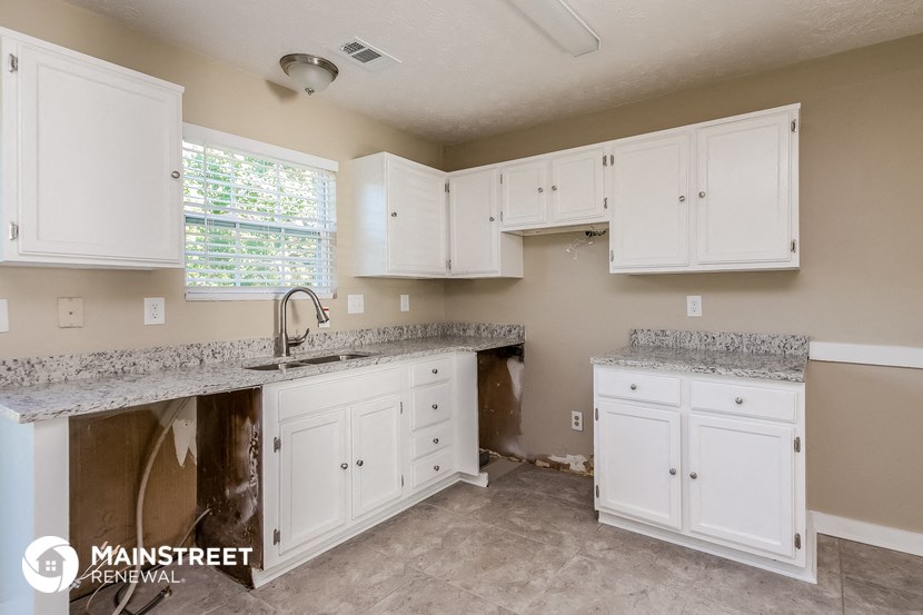 a kitchen with white cabinets and granite counter tops and a sink
