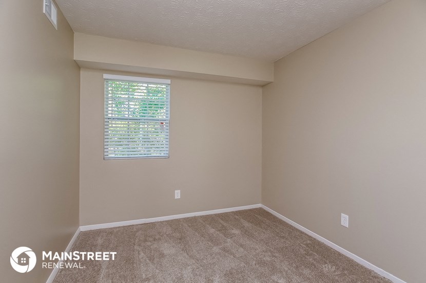 the interior of an empty room with carpet and a window
