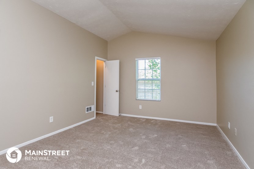the spacious living room with carpeted flooring and a window