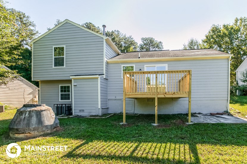 a backyard with a deck and a house with a tree stump