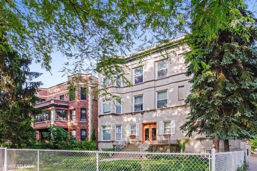the exterior of an apartment building with trees and a fence