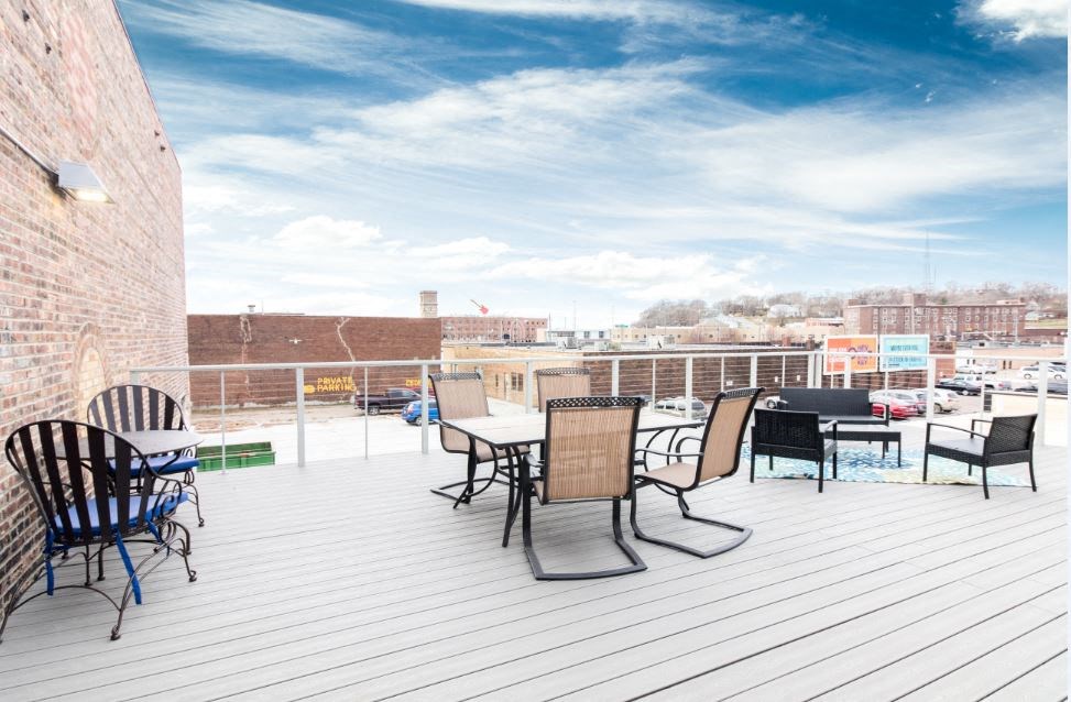 a rooftop patio with tables and chairs and a view of the city