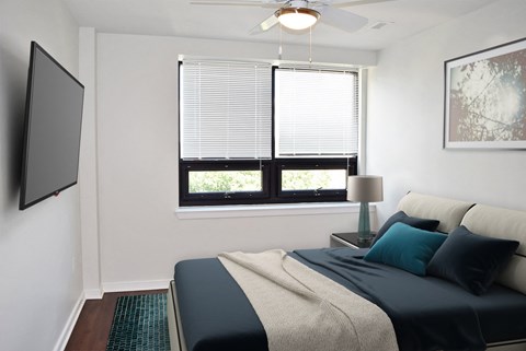 A bedroom with a bed, a window with blinds, a ceiling fan, and a painting on the wall.