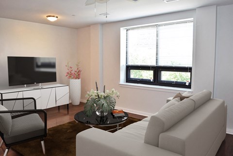 A living room with a white couch, a black chair, a coffee table, and a flat screen TV.