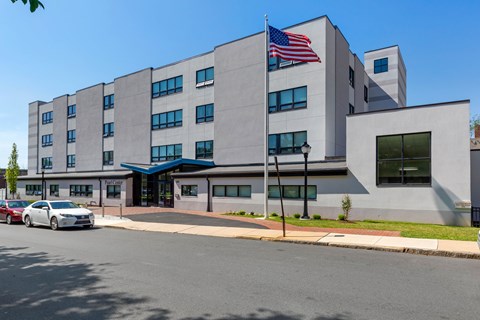 A grey building with a blue awning and an American flag on top.