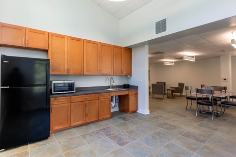 A kitchen with a black fridge and wooden cabinets.