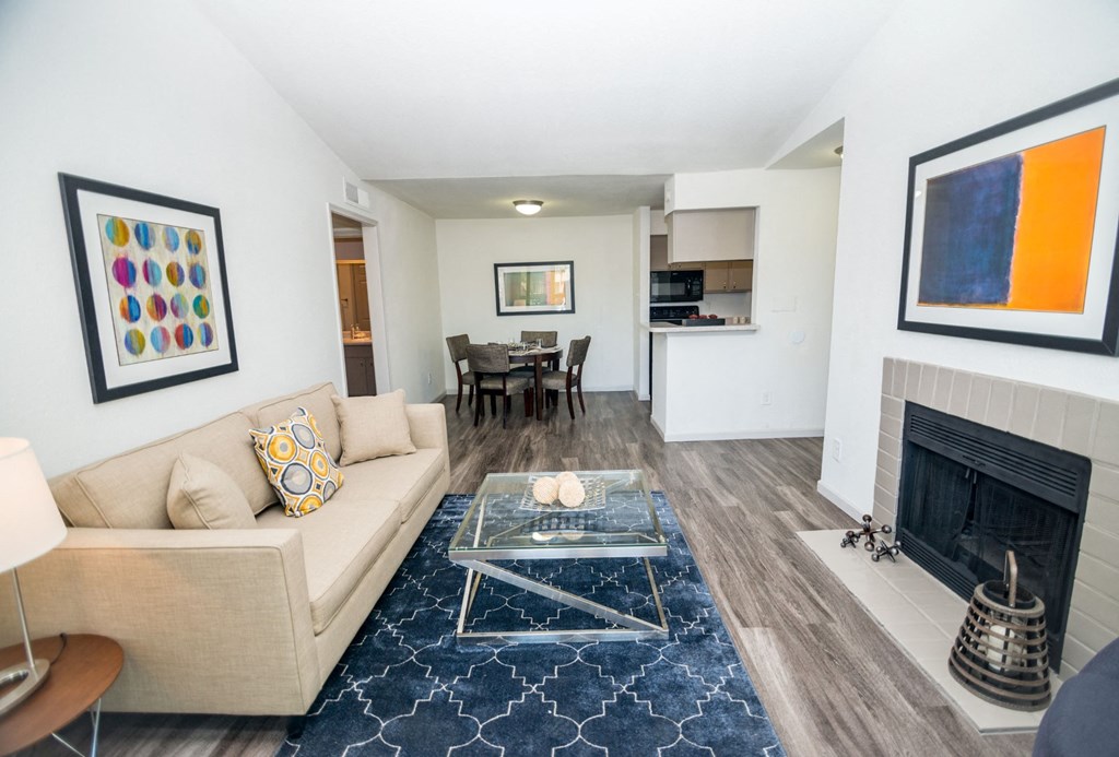 View of living room showing fireplace, vaulted ceilings, dining room, and kitchen.