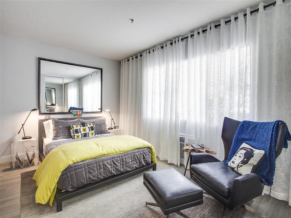 a bedroom with a bed and a chair and a mirror