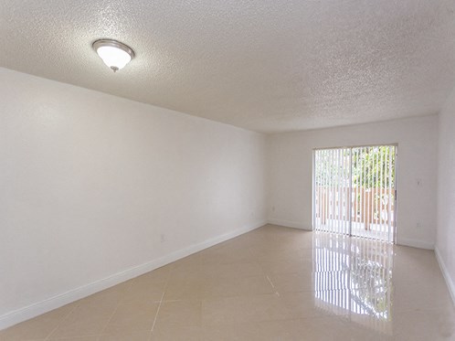 an empty living room with a sliding glass door to a patio