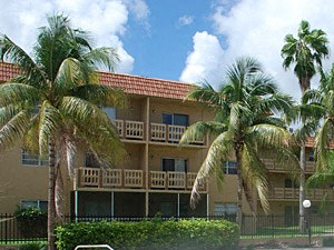 a swimming pool in front of a hotel with palm trees