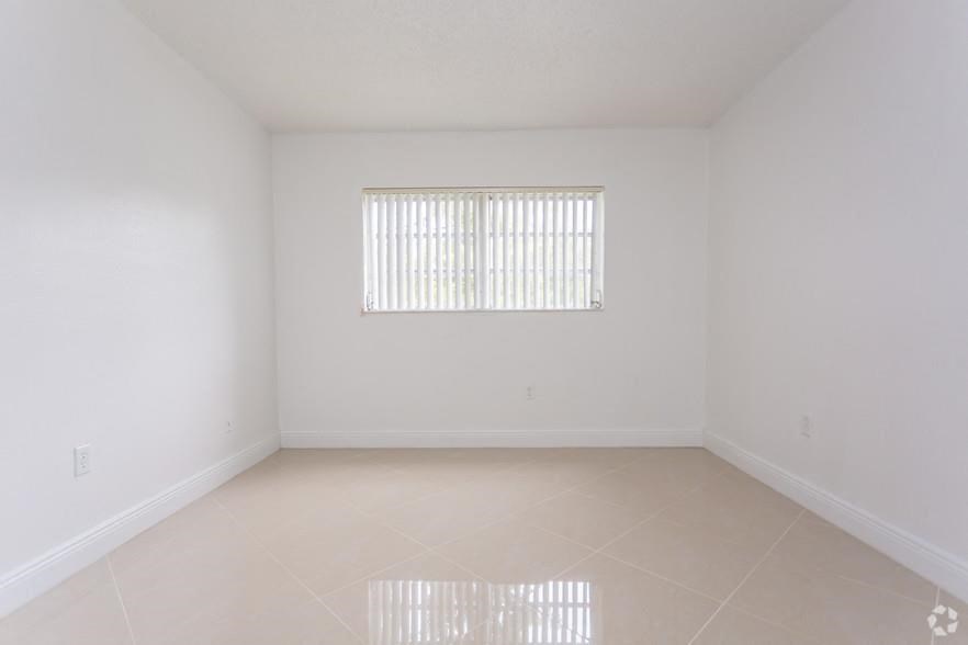 an empty living room with a window and a tiled floor