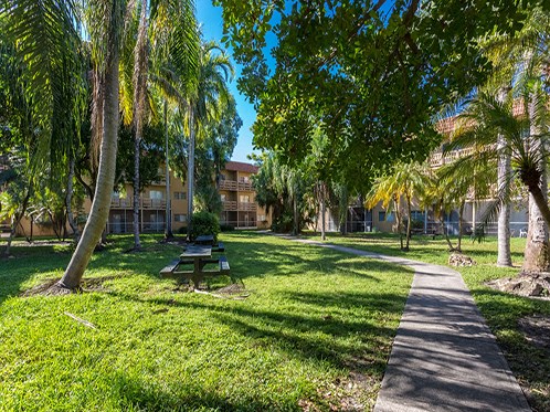 a park with a picnic table and trees in front of a building