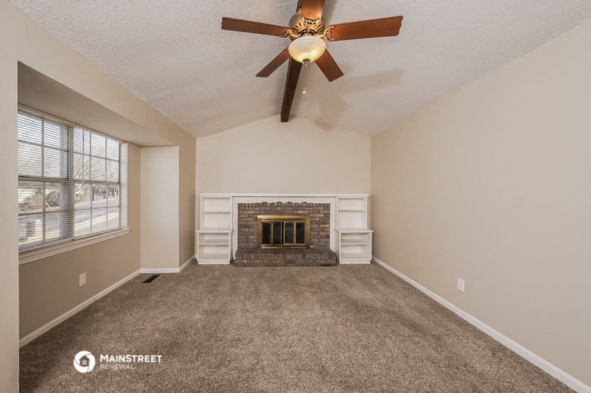 the living room has a fireplace and a ceiling fan