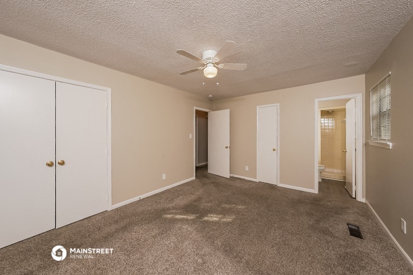 a spacious living room with carpet and a ceiling fan