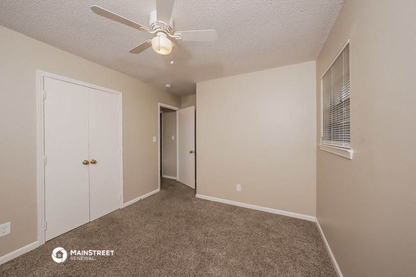 a bedroom with a ceiling fan and a door to a closet