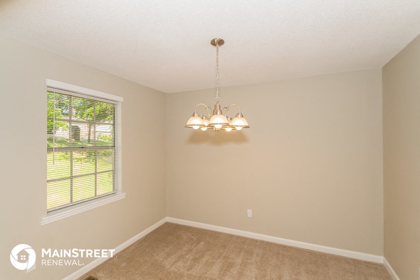 the spacious living room with a large window and a chandelier