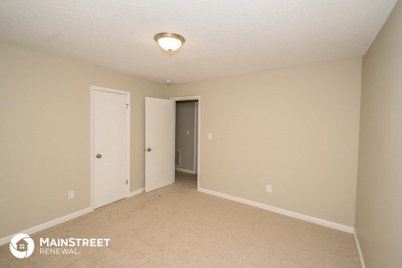 a bedroom with a carpeted floor and a door to a closet
