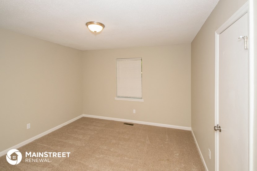 the upstairs bedroom has a carpeted floor and a window