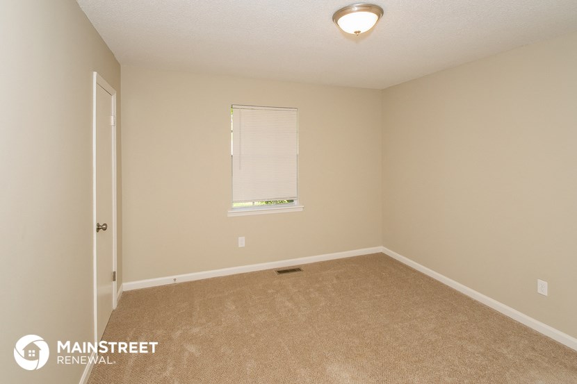 the upstairs bedroom with carpeted flooring and a window