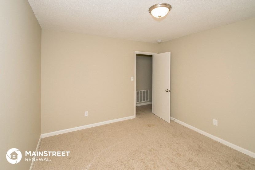 the spacious living room with carpeting and a door to the hallway