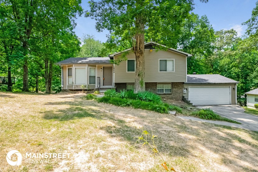 a house with a tree in the yard and a driveway