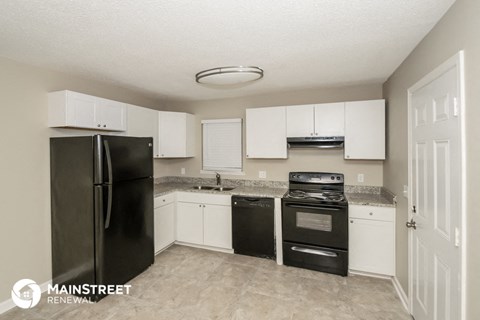 a kitchen with white cabinets and black appliances and a refrigerator