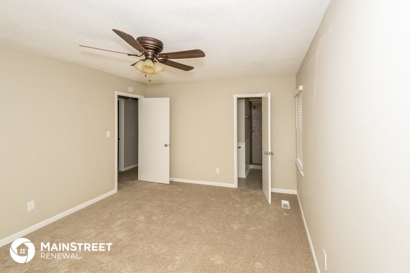 an empty living room with a ceiling fan and a hallway