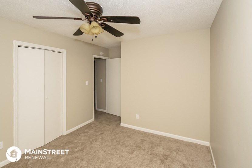 a bedroom with a ceiling fan and a closet
