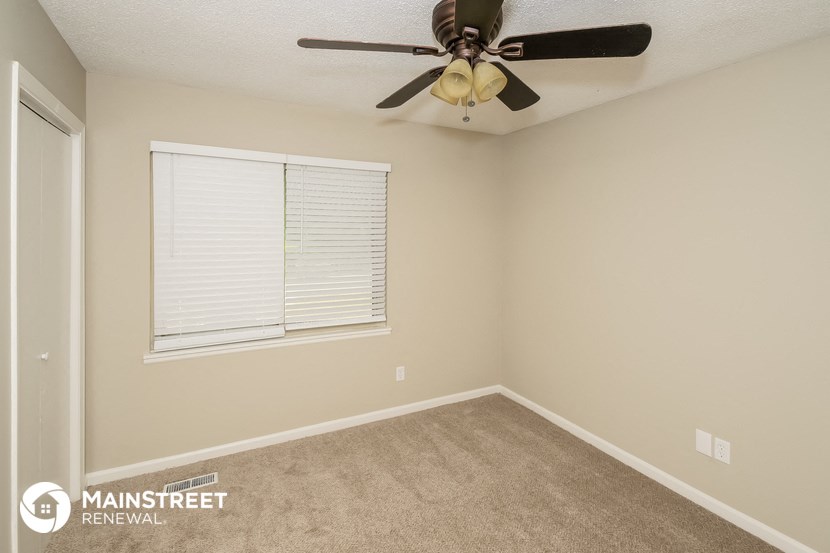the spacious bedroom has a ceiling fan and a window